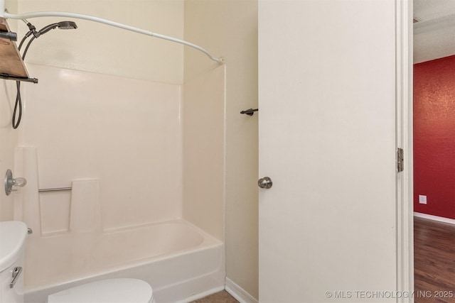 bathroom featuring toilet, baseboards, and washtub / shower combination