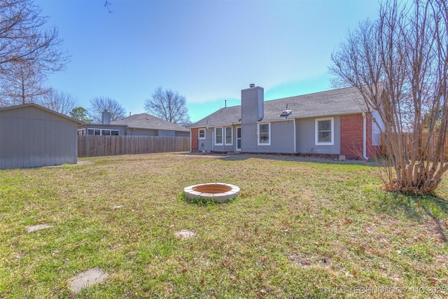 rear view of house with an outbuilding, fence, a yard, a chimney, and brick siding