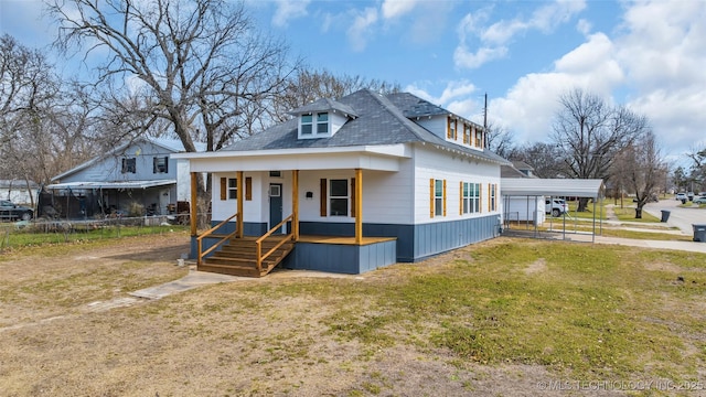 view of front of house with a trampoline, fence, a porch, a front yard, and a carport