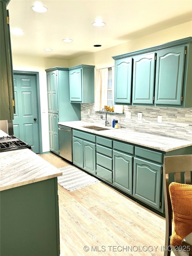 kitchen with green cabinets, dishwasher, decorative backsplash, light wood-style floors, and a sink