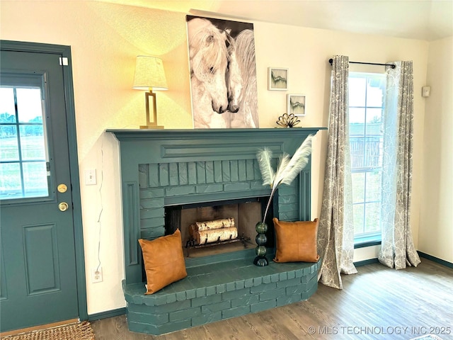 sitting room with baseboards, a brick fireplace, and wood finished floors