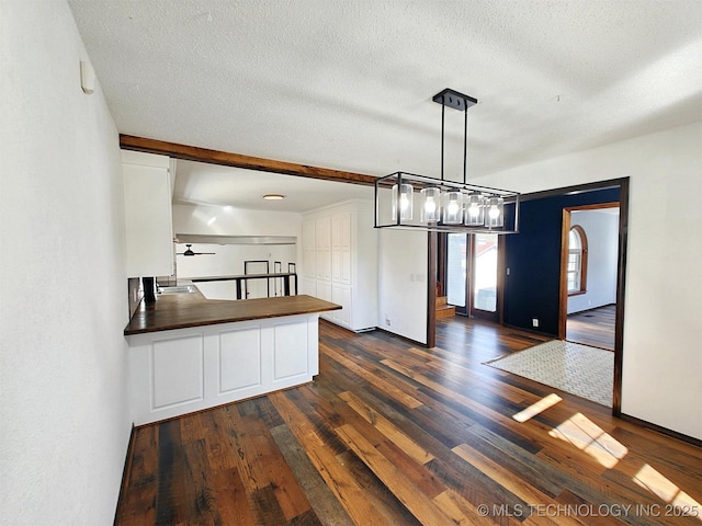 unfurnished dining area with a textured ceiling, dark wood-style flooring, and a sink