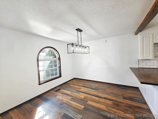 unfurnished dining area with dark wood finished floors, visible vents, and a textured ceiling