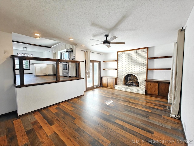 unfurnished living room featuring a fireplace, a textured ceiling, ceiling fan, and wood finished floors