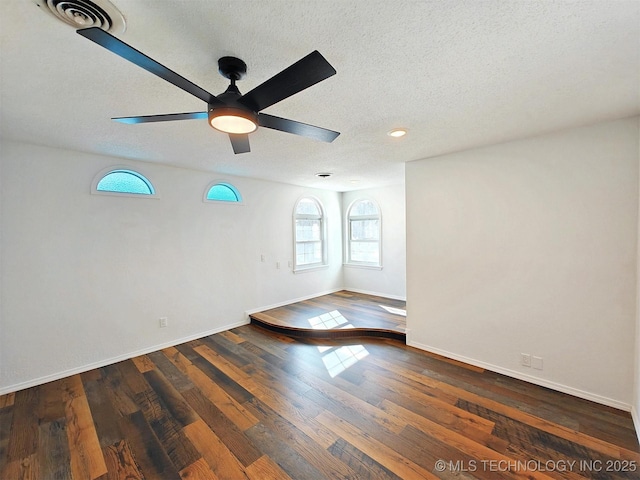 unfurnished room with visible vents, baseboards, wood finished floors, a textured ceiling, and a ceiling fan