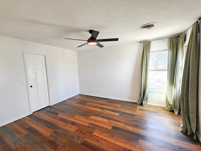 unfurnished room featuring a ceiling fan, baseboards, visible vents, dark wood-style flooring, and a textured ceiling