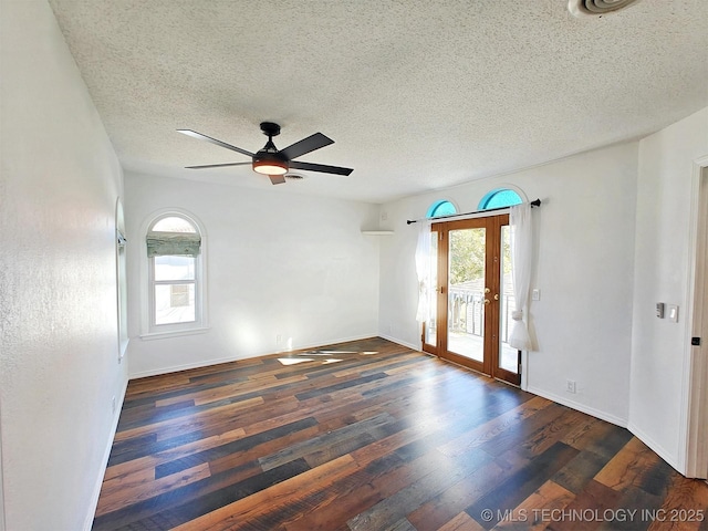 unfurnished room featuring a healthy amount of sunlight, ceiling fan, baseboards, and wood finished floors