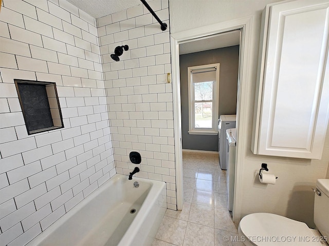 bathroom featuring tile patterned floors, toilet, bathing tub / shower combination, and washing machine and clothes dryer