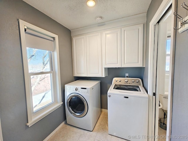 laundry area with cabinet space, plenty of natural light, independent washer and dryer, and light tile patterned floors