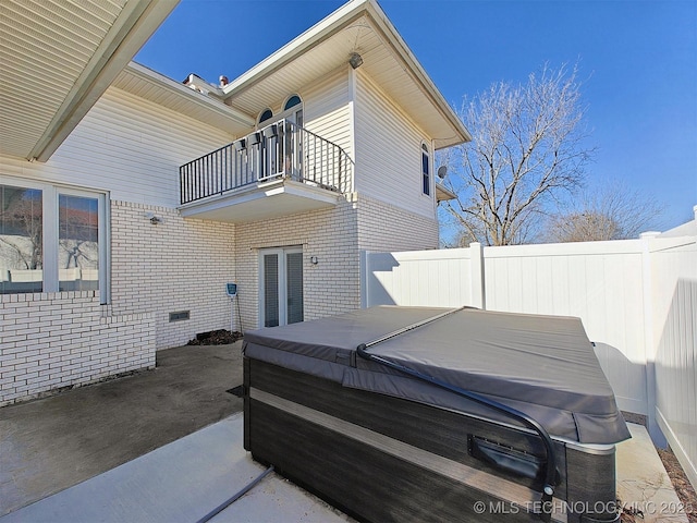 view of patio / terrace with a hot tub, a balcony, and fence