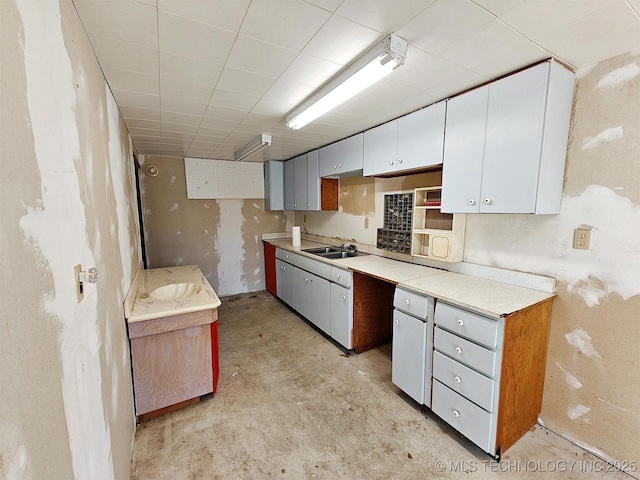 kitchen with white cabinetry, light countertops, unfinished concrete flooring, and a sink