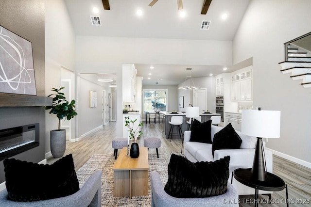 living area featuring light wood finished floors, visible vents, and a glass covered fireplace