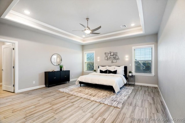 bedroom with multiple windows, a tray ceiling, and wood finished floors