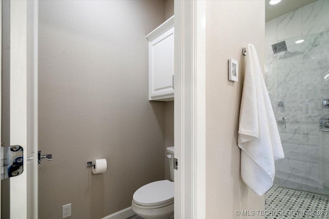 bathroom with a stall shower, toilet, and baseboards