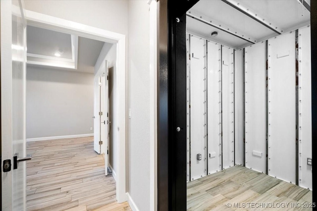 hallway featuring baseboards and wood finished floors