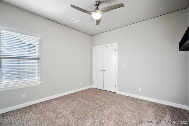 unfurnished bedroom featuring visible vents, baseboards, carpet floors, a closet, and a ceiling fan