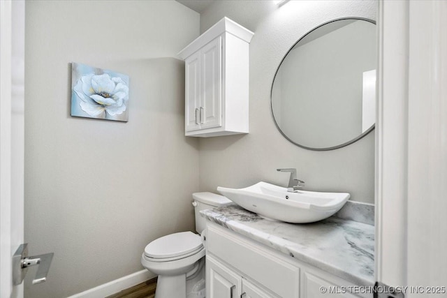 bathroom featuring vanity, toilet, wood finished floors, and baseboards