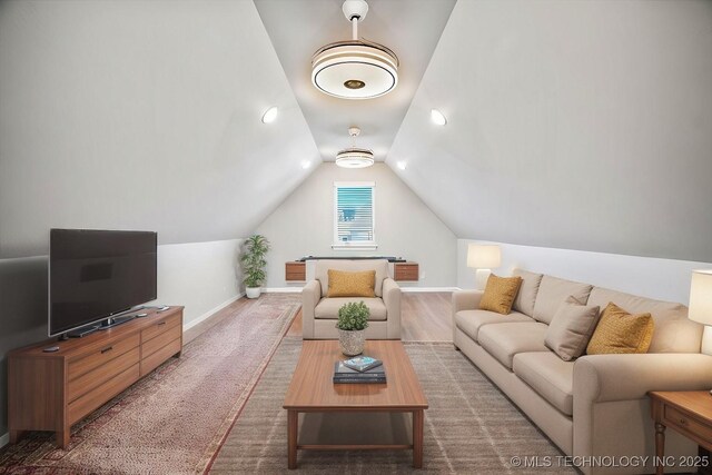 living room featuring baseboards and vaulted ceiling