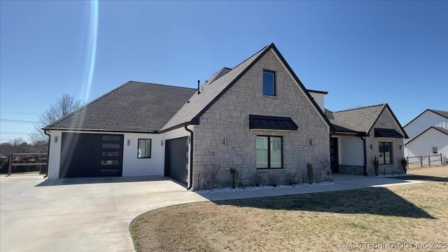 view of front of house with stone siding, driveway, fence, and a garage