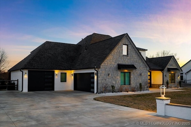 view of front facade with an attached garage, driveway, and a shingled roof