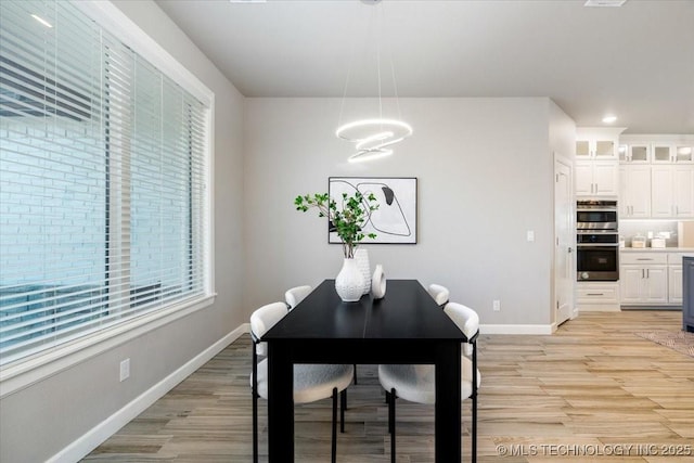 dining space with light wood-type flooring and baseboards