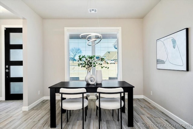 dining space featuring light wood-style floors, visible vents, and baseboards