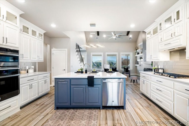 kitchen with a sink, appliances with stainless steel finishes, light countertops, and white cabinetry