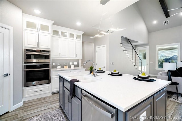 kitchen featuring gray cabinets, a sink, stainless steel appliances, white cabinets, and light countertops