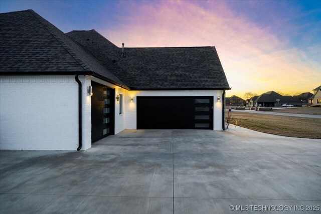 garage at dusk featuring driveway