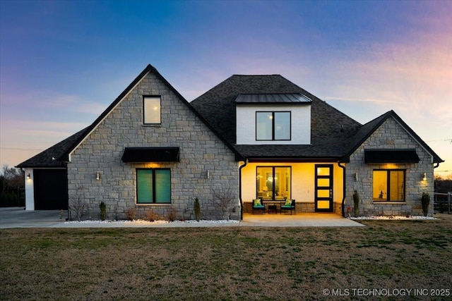 view of front facade featuring a shingled roof, a yard, driveway, and metal roof