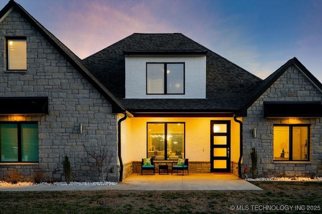 back of property featuring a patio and roof with shingles