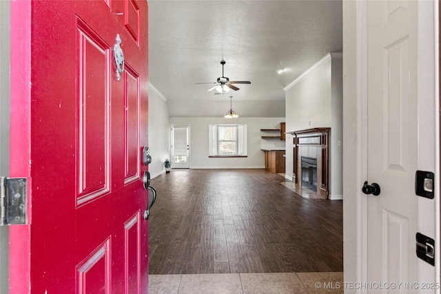 foyer featuring a fireplace, wood finished floors, a ceiling fan, and ornamental molding