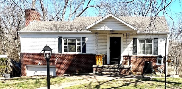 view of front of home with brick siding, a chimney, an attached garage, and a shingled roof