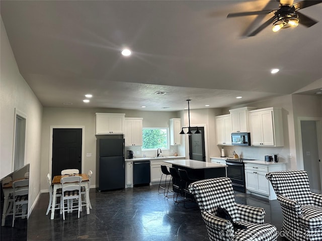 kitchen featuring a kitchen bar, black appliances, light countertops, and a center island