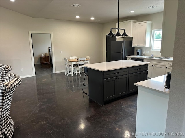 kitchen featuring visible vents, a kitchen breakfast bar, white cabinets, and freestanding refrigerator