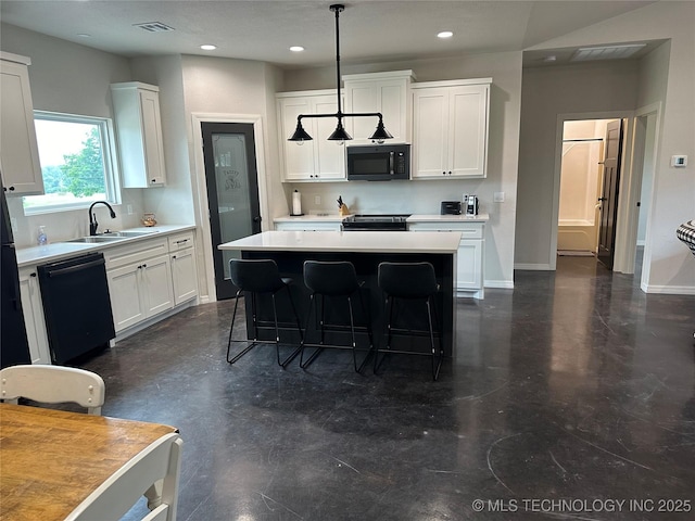 kitchen featuring black appliances, a breakfast bar, a center island, white cabinets, and light countertops