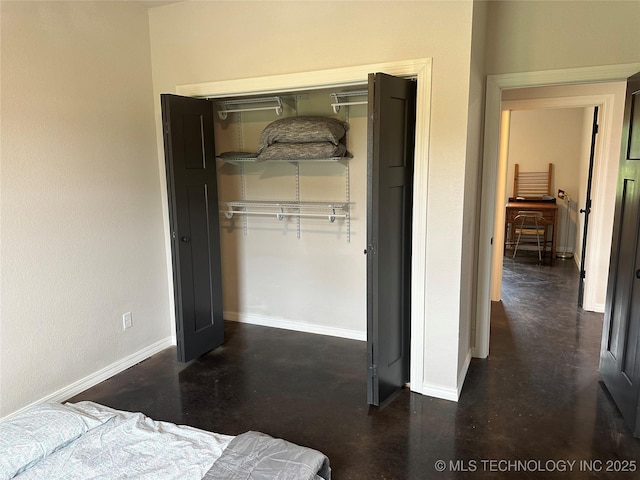 bedroom featuring baseboards, a closet, and finished concrete floors