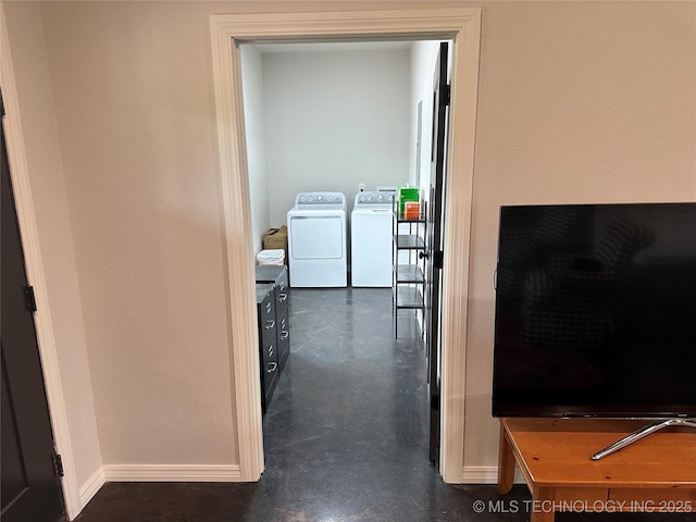 hallway featuring finished concrete flooring, baseboards, and washing machine and clothes dryer