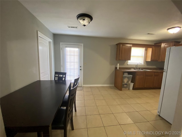 kitchen with visible vents, baseboards, freestanding refrigerator, light tile patterned flooring, and a sink