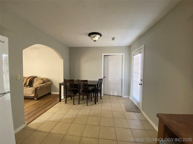 dining room with visible vents, arched walkways, baseboards, and light tile patterned flooring