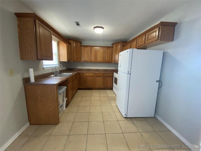191 W Senior St, Colcord, OK 74338 - kitchen with freestanding refrigerator, a sink, brown cabinets, dark countertops, and light tile patterned floors