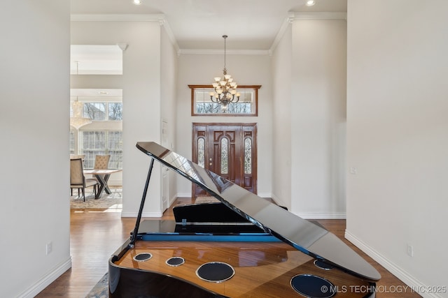 entrance foyer with crown molding, a notable chandelier, wood finished floors, and baseboards