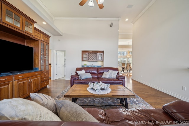 living area featuring dark wood-type flooring, baseboards, ornamental molding, recessed lighting, and a ceiling fan