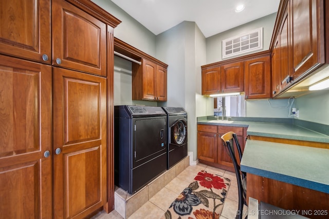 laundry area featuring cabinet space, light tile patterned flooring, washing machine and dryer, and a sink