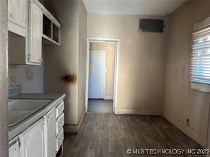 kitchen featuring white cabinetry, dark wood-type flooring, baseboards, and a sink