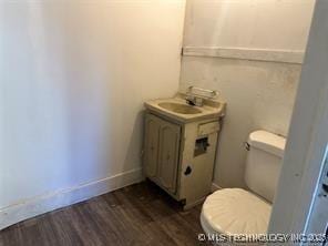 bathroom featuring toilet, vanity, baseboards, and wood finished floors