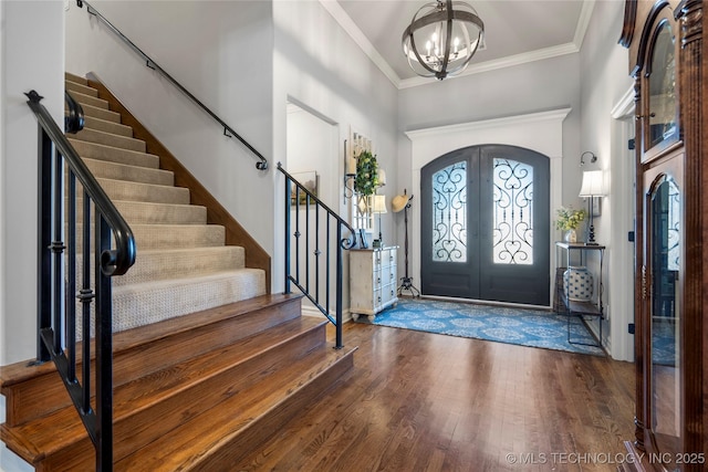 entryway with stairway, wood finished floors, french doors, crown molding, and a chandelier