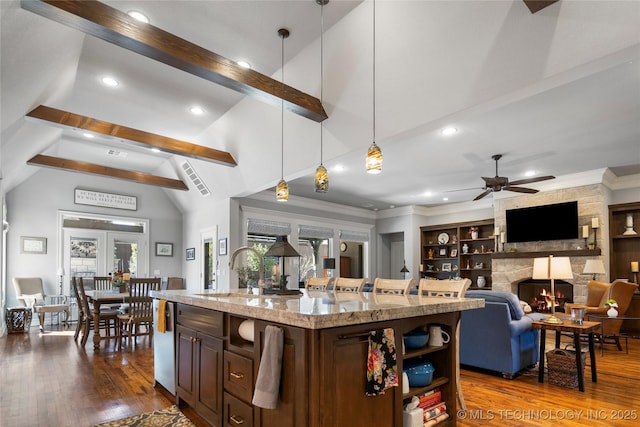 kitchen with beamed ceiling, pendant lighting, dark wood-style flooring, a fireplace, and a sink