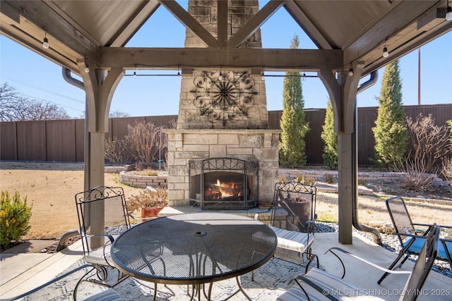 view of patio / terrace with a fenced backyard and an outdoor stone fireplace