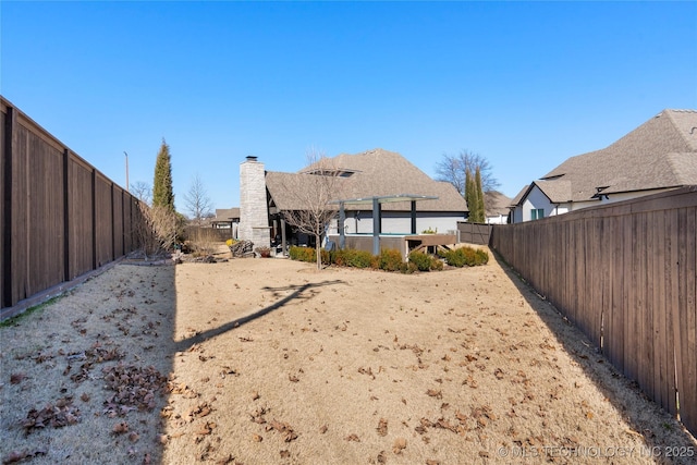 back of property featuring a chimney and a fenced backyard